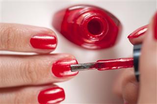 A woman applying red nail polish