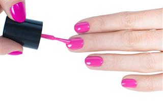 Female hands being manicured with pink nail paint