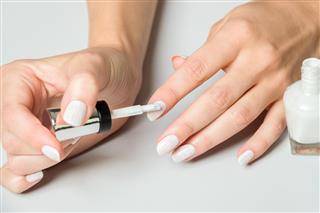 Woman Applying White Polish to Finger Nails