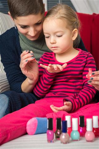 Mother and daughter having fun painting fingernails, family time concept