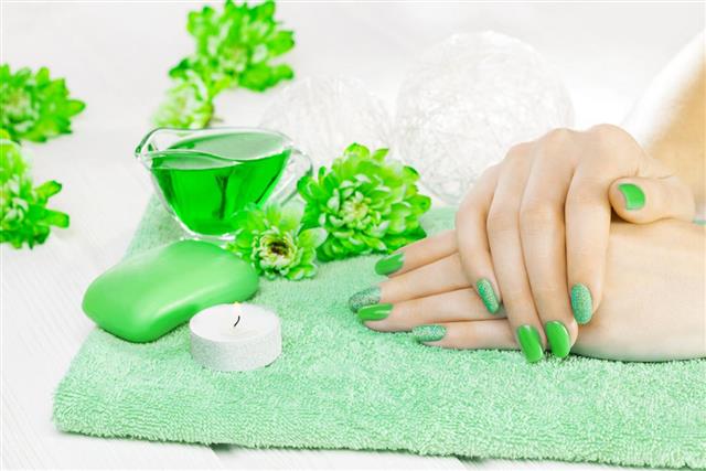 Beautiful green manicure with chrysanthemum and towel on the white wooden table