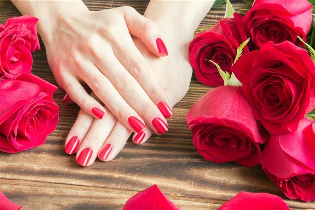 Red nail manicure with red roses around