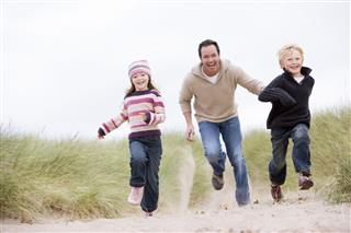 Father And Children Running At Beach