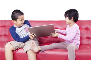Two Children Fighting Over A Laptop