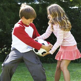 Young Boy And Girl Playing Football