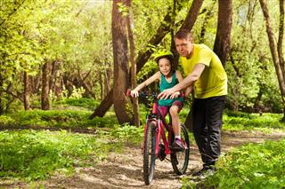 Father Teaching Daughter To Ride Bicycle