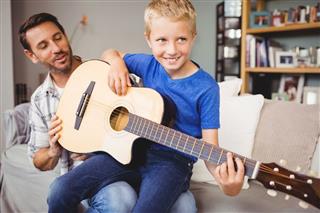 Happy Man Teaching Guitar To Son