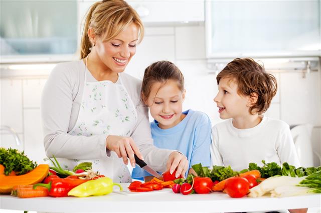 Mother And Children Cutting Vegetables