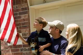 Family putting up American flag at home. Father, son, mother