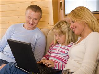 Parents And Daughter Using Laptop