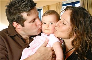 Parents Kissing Their Baby Girl