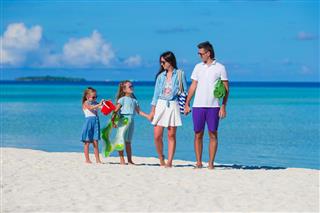 Happy family of four on white beach