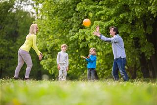 Happy family playing with ball in the park