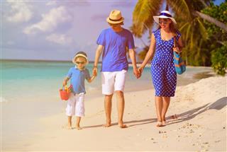 Family with child walking on tropical sand beach
