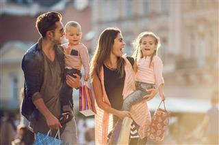 Young cheerful family shopping together in the city