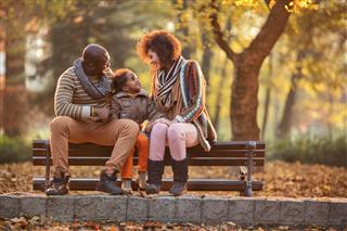 African American family relaxing on bench in the autumn park