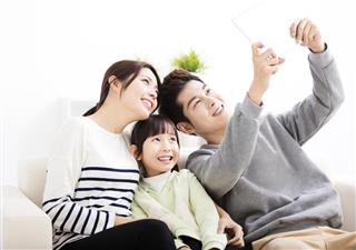 Happy young family taking selfie on sofa