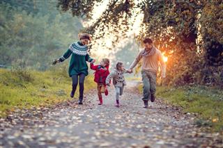 Young playful family having fun while running in the park