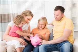 Family Saving Money In Piggy bank