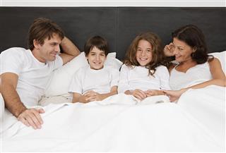 Family sitting up in bed