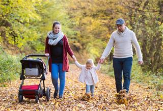 Beautiful young family on a walk in autumn forest