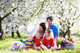 Big family with three kids on picnic in spring garden
