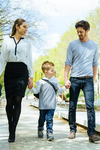 Happy Family Walking Through The Park Taking Son to School