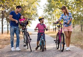 Smiling parent and children with bicycles in the park