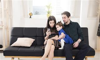 Young family looking at mobile phone at home