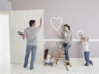Man and woman with boy and girl painting hearts on wall