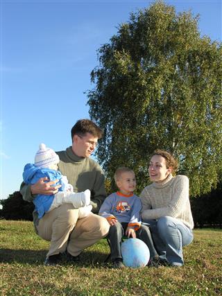 Family of four on grass blue sky autumn