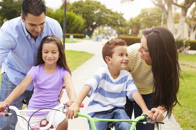 Parent Teaching Children To Ride Bikes In Park