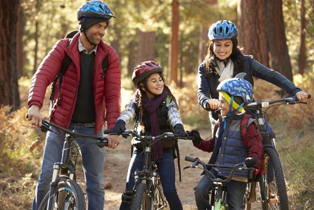 Hispanic family on bikes in a forest looking at each