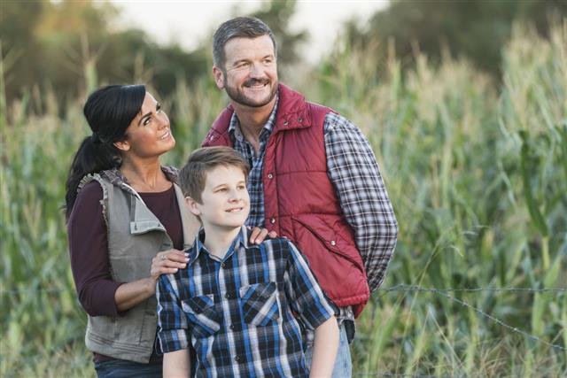 Family with teenage son on a farm by corn field