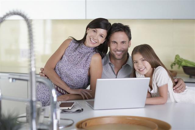 Family Using Laptop In Kitchen