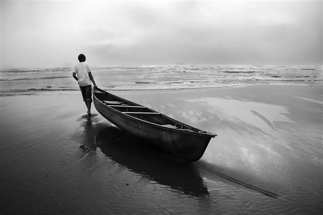 Man Dragging Canoe Boat Into Ocean