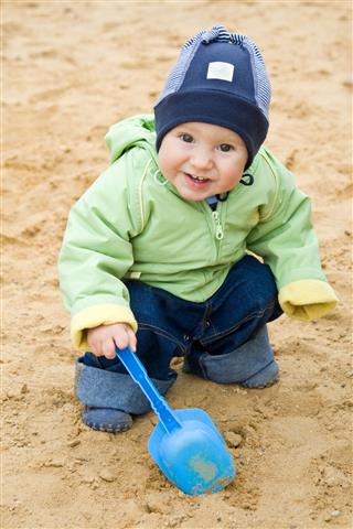 Child With The Scoop In A Sandbox