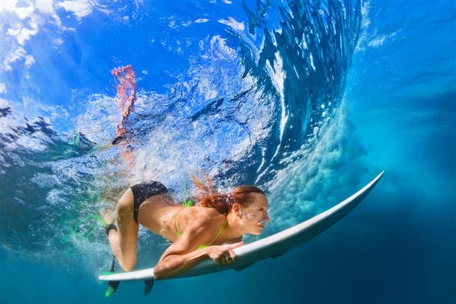 Fille plongeant avec une planche de surf