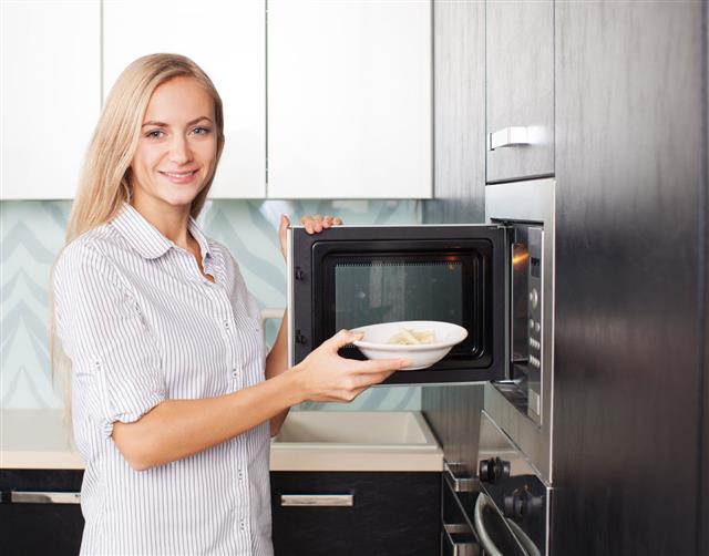 Woman Warms Up Food In The Microwave