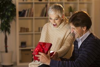 Cheerful Mature Couple Opening Christmas Present