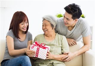Couple Giving Present To Grandmother