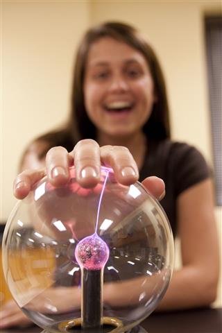 Female Student Touching A Plasma Ball