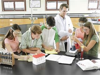 Teacher And Teenagers Doing Experiment