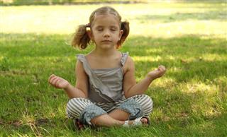 Little girl meditating in park