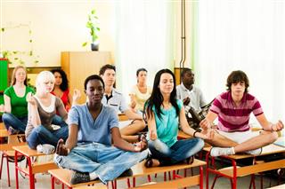 Group of teenagers sitting on the desk in lotus position