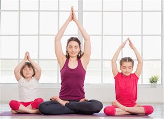 Young mother and daughters sitting in lotus position