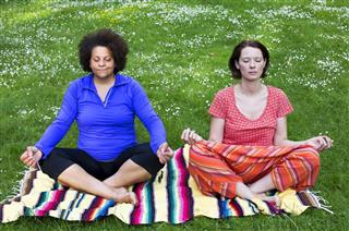Two women meditating in park