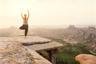 Young woman practicing yoga at mountain cliff on sunrise