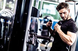 Muscular Fit Man Exercising in a Gym