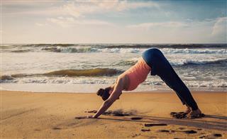 Young sporty fit woman doing yoga oudoors at tropical beach